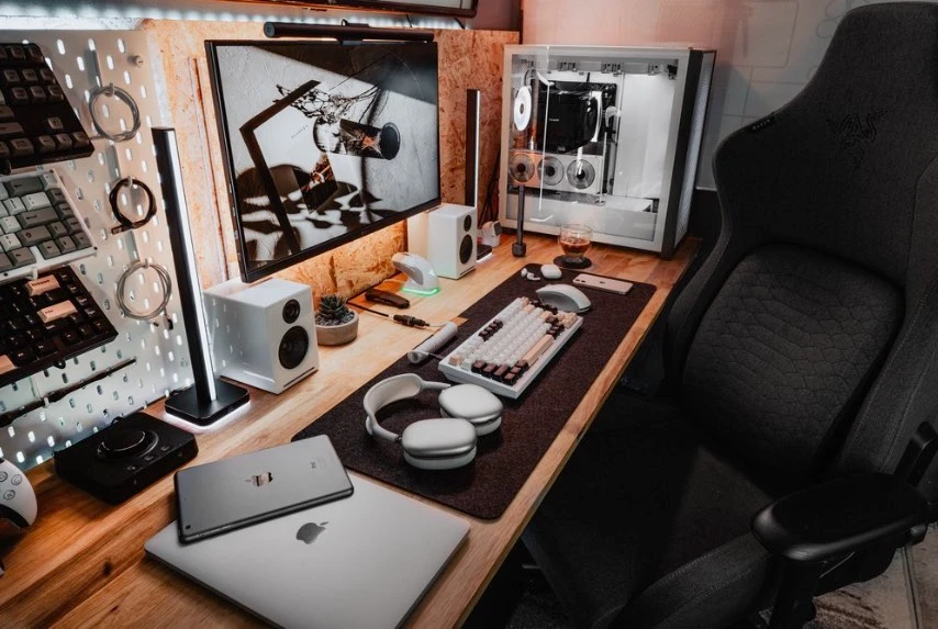 TheBucketListTech's value-focused desk setup with a custom PC build, LG ultrawide monitor, MacBook, mechanical keyboards on a pegboard, and speakers