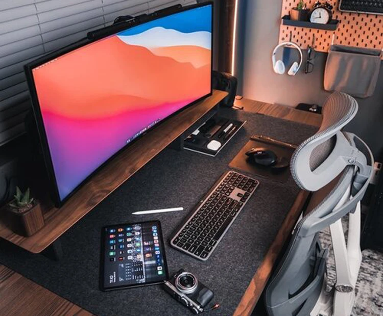 Lloyd Carig's clean minimal desk setup in Vancouver BC with dual monitors, Fujifilm camera, and neatly organized peripherals