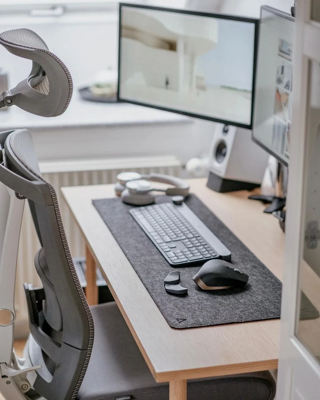 Jensen's minimal Scandinavian desk setup with dual monitors, mechanical keyboard, mouse, headphones, and ergonomic office chair